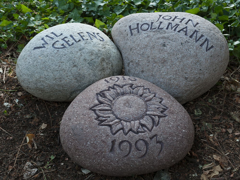 Drie zwerfstenen of granietkeien met gebeeldhouwde zonnebloem en met hand-gekapte letters
