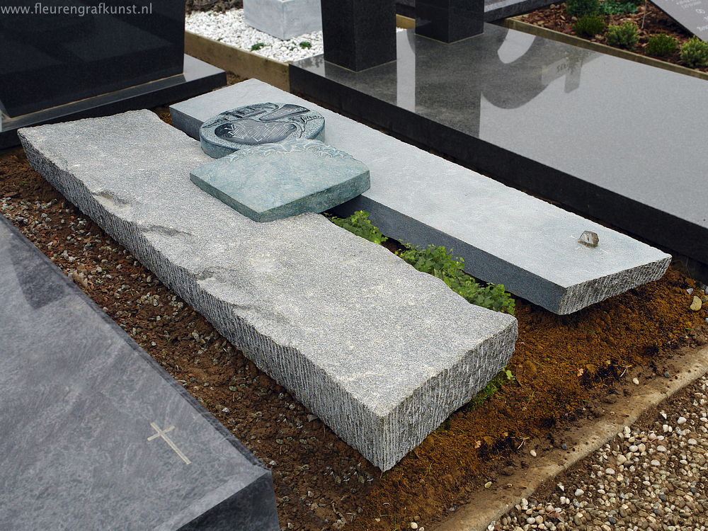 Ruwe granieten grafsteen met 2 penningen van de edele gepolijste steensoort diabas met handmatig gehakte afbeeldingen geklemd tussen de dubble korstplaat (croute) - (grafstenen in de regio Zuid-Limburg: Maastricht-Heerlen-Geleen)