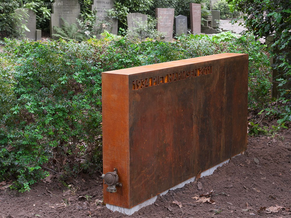 Grote grafsteen van beton en cortenstaal met bronzen stopkontakt. De betonnen sokkel staat op een begraafplaats Bieberg in Breda