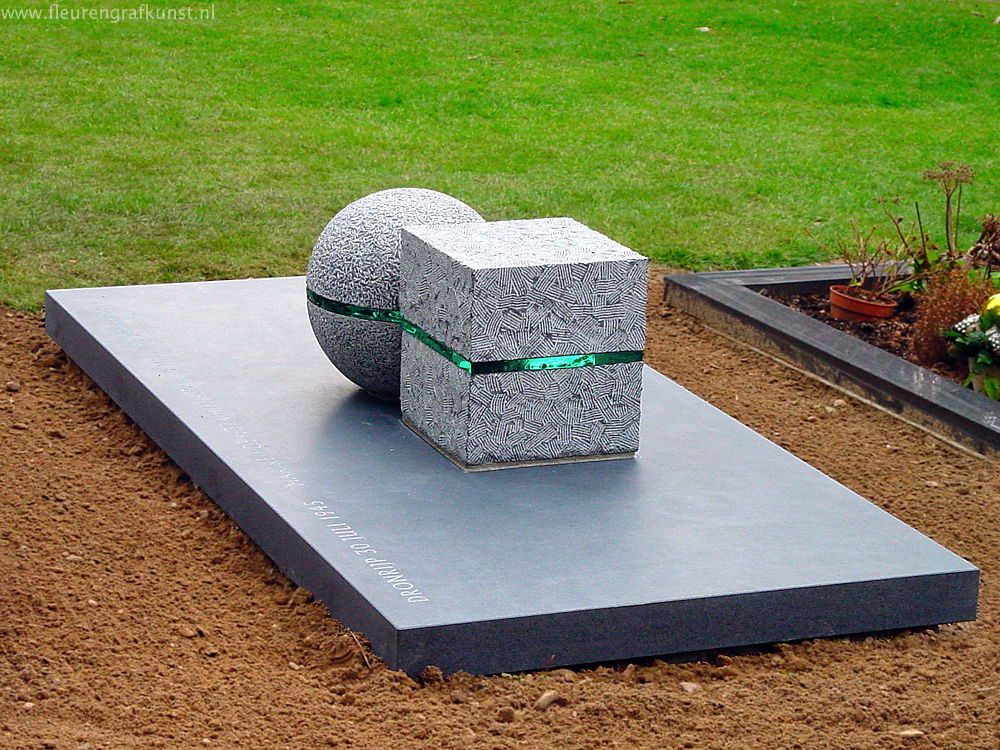 Grafsteen met glas - een bol en een kubus van hand-gehakt Belgische hardsteen en met dik glas daartussen gelijmd op een lage sokkel van gezoet graniet in Wageningen