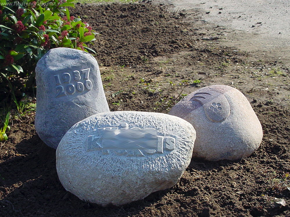 Grafmonument van drie zwerfstenen met teksten en bloemmotief in Eindhoven