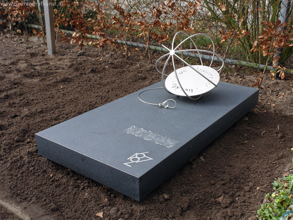 Kindergraf van roest-vrij-staal: een losse strandbal van RVS op een vlak van mat gezoete graniet