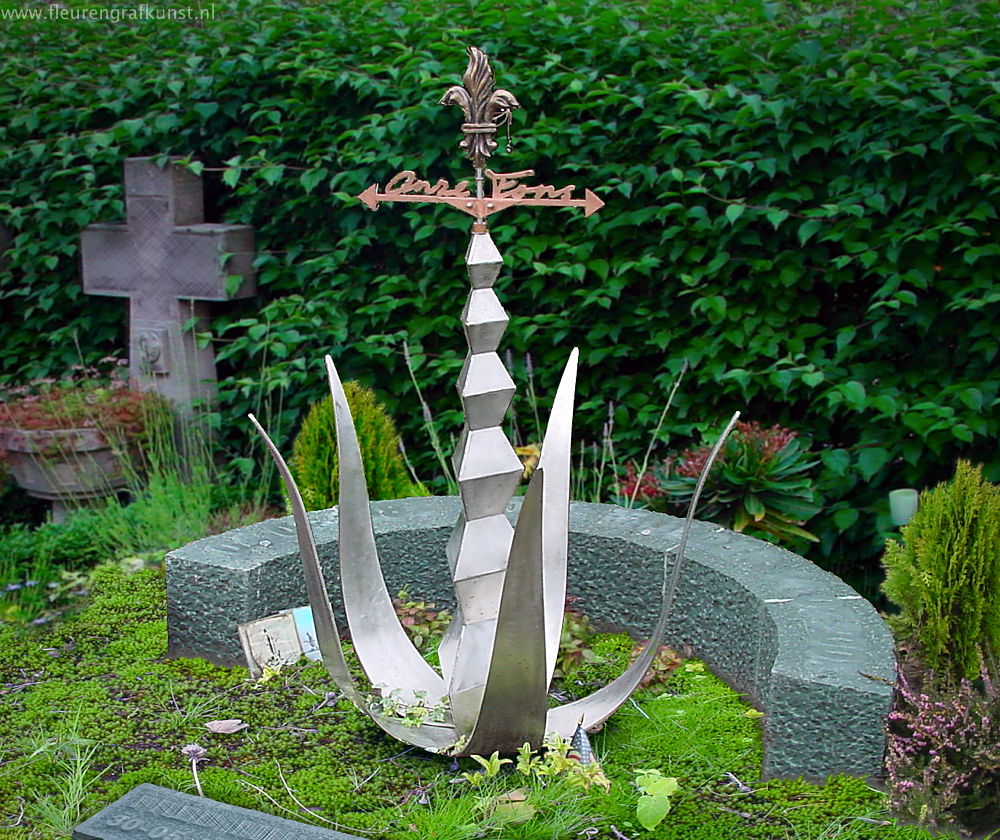 Een gestileerde plantmet windwijzer als graf: agave van rvs, omgeven door blokken natuursteen met naam en data