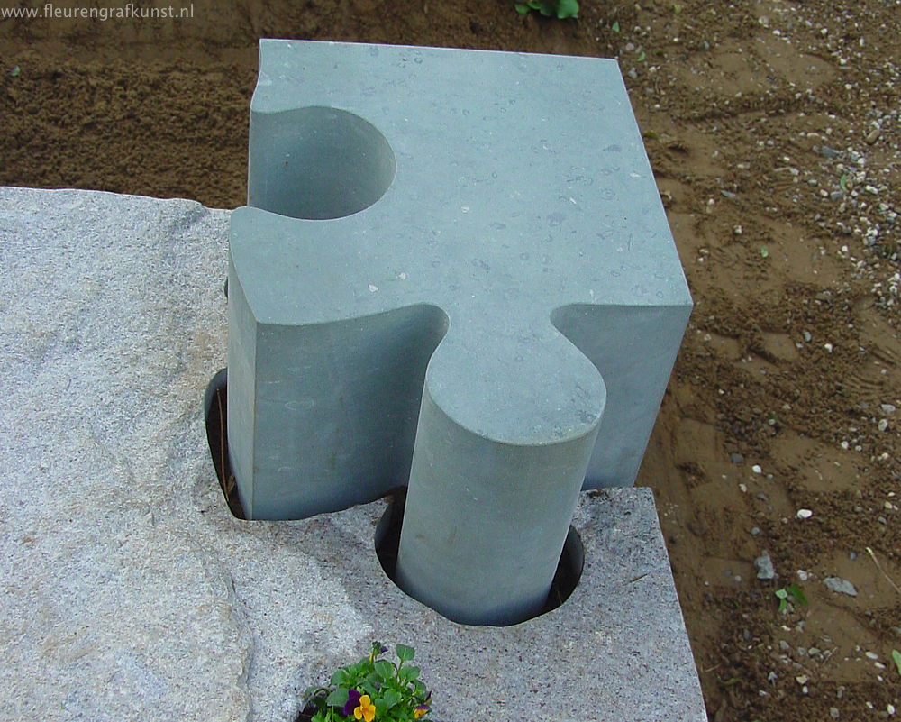 Groot puzzelstuk uit natuursteen gezaagd is hier zetel of zitbank bij een graf (grafsteen Roermond)